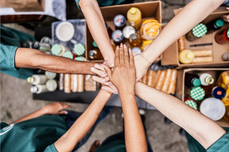 close-up of volunteers with hands stacked during donation event outdoors