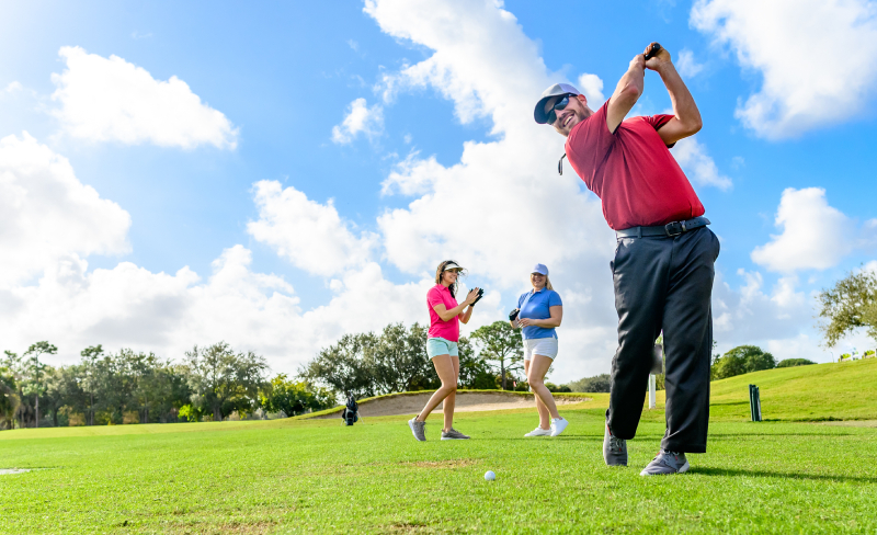 Trio plays golf on a beautiful scenic green, man and two women sporty